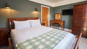 A bedroom with a bed, wooden nightstands, a dresser, a desk, and a television on the wall. - Host Stay Fauna (Whitby)