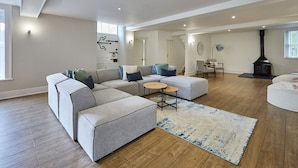 A modern living room with a sectional sofa, a round coffee table, and a fireplace. - Host Stay Stay House (Thirsk)