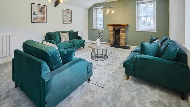 A living room with two green sofas, a round coffee table, and a fireplace. - Host Stay Stay House (Thirsk)
