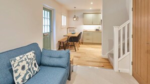 A compact living space with a sofa, a dining table, and a kitchen area. - Host Stay Breckon Cottage (Whitby)