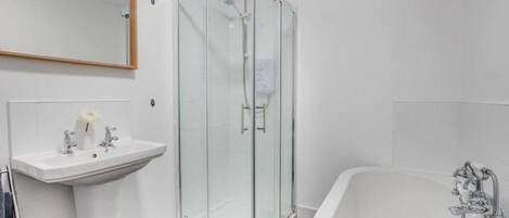 A modern bathroom with a glass-enclosed shower, a white sink, and a freestanding bathtub.