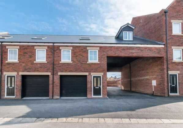 A brick building with two garage doors and a covered entrance. - Apartments in Skinningrove, Cattersty Sands Beach (Saltburn-by-the-Sea)
