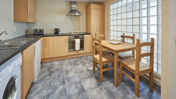 Una cucina con mobili in legno, un piano cottura, una lavastoviglie e un tavolo da pranzo con sedie.