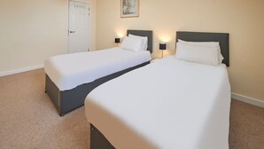 Una camera d'albergo con due letti, una porta e un quadro appeso al muro.