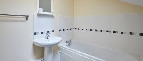 A bathroom with a white sink, a mirror, and a bathtub.