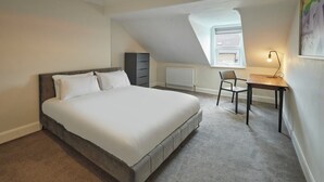 Une chambre à coucher avec un grand lit, un bureau, une chaise, un radiateur et une fenêtre donnant sur un beau paysage.