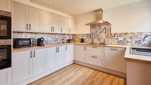 A modern kitchen with white cabinets, a wooden countertop, and patterned backsplash tiles. - Host Stay Darcey House (Scarborough)