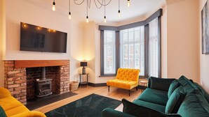 A living room with a fireplace, a sofa, a yellow armchair, and a green sofa. - Host Stay Darcey House (Scarborough)