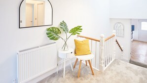 A staircase with a white railing, a plant on a small table, and a mirror on the wall. - Host Stay Marshlands (Redcar)
