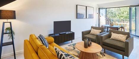A modern living room with a sofa, armchairs, a coffee table, and a TV.