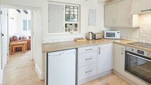 Eine kompakte Küche mit weißen Schränken, einem eingebauten Geschirrspüler, einer Mikrowelle und einem Backofen.