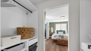 A walk-in closet with storage bins and baskets, a bed with a wooden headboard, and a green wall in the adjacent bedroom. - Backyard Summer Getaway Great for Family & Friends- Close to Convention Center! (Reno)