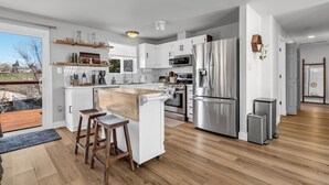 A modern kitchen with white cabinets, stainless steel appliances, and a wooden island. - Backyard Summer Getaway Great for Family & Friends- Close to Convention Center! (Reno)