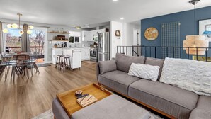 A modern living room with a grey sofa, wooden coffee table, and a dining area with a round table and chairs. - Backyard Summer Getaway Great for Family & Friends- Close to Convention Center! (Reno)