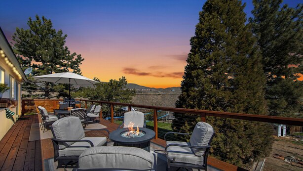 A deck with outdoor furniture, a fire pit, and a view of the sunset. - Backyard Summer Getaway Great for Family & Friends- Close to Convention Center! (Reno)