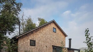 A modern house with a sloped roof, a chimney, and a wooden deck.