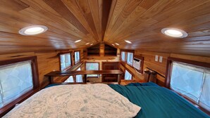 A cabin interior with a bed, a table, and a window. - Pleasant Grove Tiny Home! (Pell City)