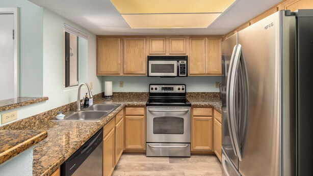 A kitchen with wooden cabinets, a stainless steel refrigerator, a microwave, and a double oven. - 1 Bedroom Condo, Sparkling Pool, Fitness Center, Pets Welcome (Glendale)