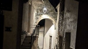 A narrow alleyway with a stone floor, a wooden bench, and a staircase leading to an upper level. - La Dimora nelle Rue (Civitella Roveto)