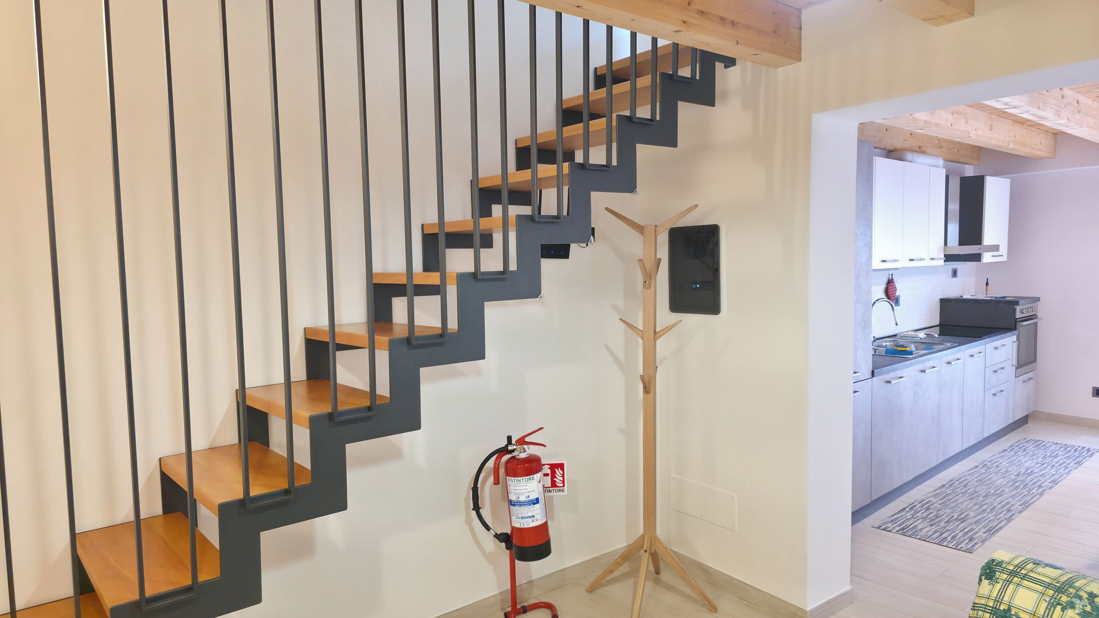 Ein modernes Interieur mit einer Holztreppe, einer Küchenzeile und einem Feuerlöscher.