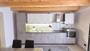 A modern kitchen with a wooden ceiling, white cabinets, a stainless steel sink, and an oven. - La Dimora nelle Rue (Civitella Roveto)