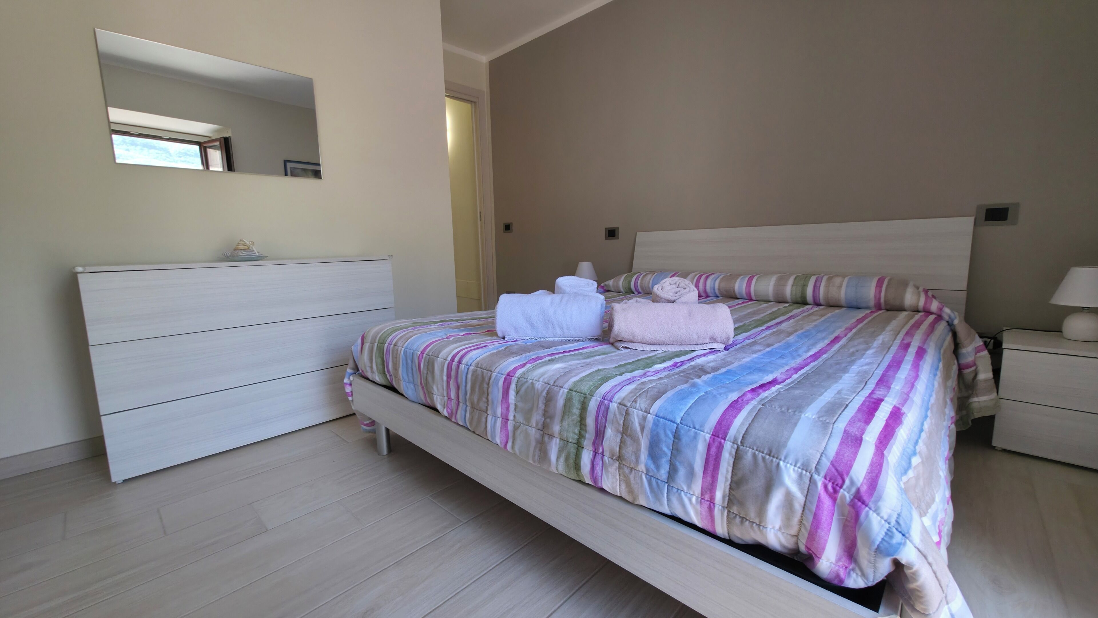 Une chambre à coucher comprenant un lit, une commode, une table de chevet et un miroir.