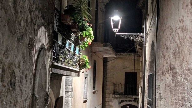 A narrow alleyway with stone walls, a street lamp, and a building with a dark door and windows. - La Dimora nelle Rue (Civitella Roveto)
