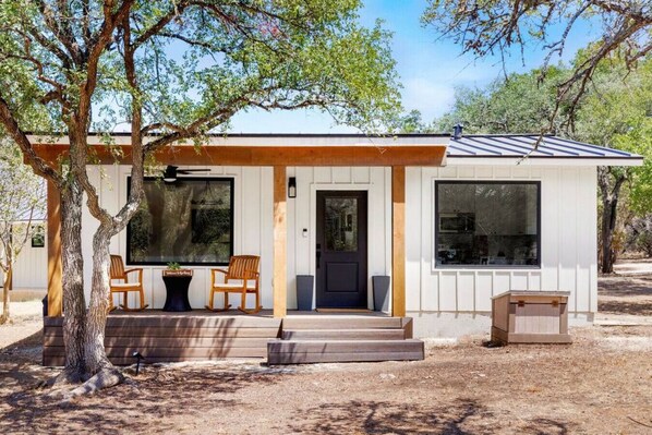 A modern house with a covered porch, large windows, and a small front yard.