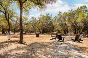 An outdoor patio area with stone flooring, a hammock, and outdoor furniture.