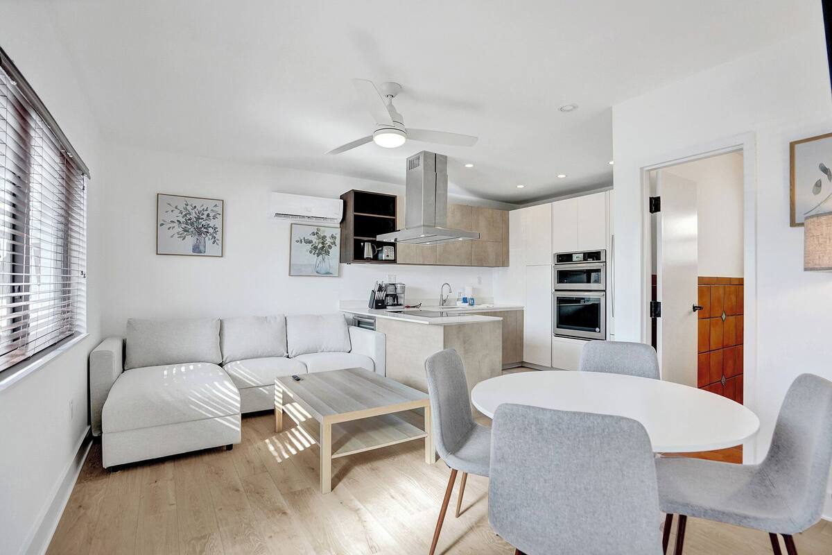 Una cocina moderna con una isla central, horno empotrado y ventilador de techo.
