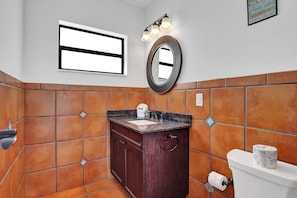 A bathroom with a vanity, sink, mirror, and toilet. - Waves on Walnut (Hollywood)