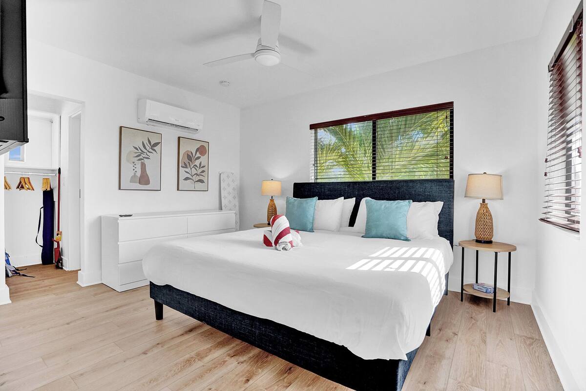 Un dormitorio moderno con una cama grande, ventilador de techo y ventana con persianas.