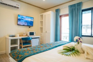 Habitación de hotel con una cama, un escritorio con silla, televisor y ventana con cortinas.