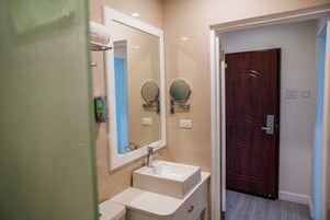 Un baño con un lavamanos blanco, dos espejos redondos y una puerta de madera.
