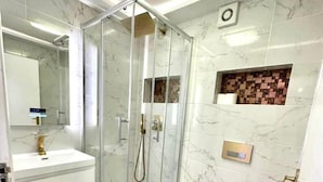 A modern bathroom with a glass-enclosed shower, a white sink, and a toilet. - 3 Bedroom Riverview Flat Canary Wharf Free Parking (London)