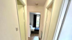 A narrow hallway with wooden flooring and white walls. - 3 Bedroom Riverview Flat Canary Wharf Free Parking (London)