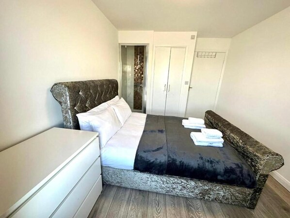Une chambre à coucher avec un lit, une table de chevet, une armoire et une porte.