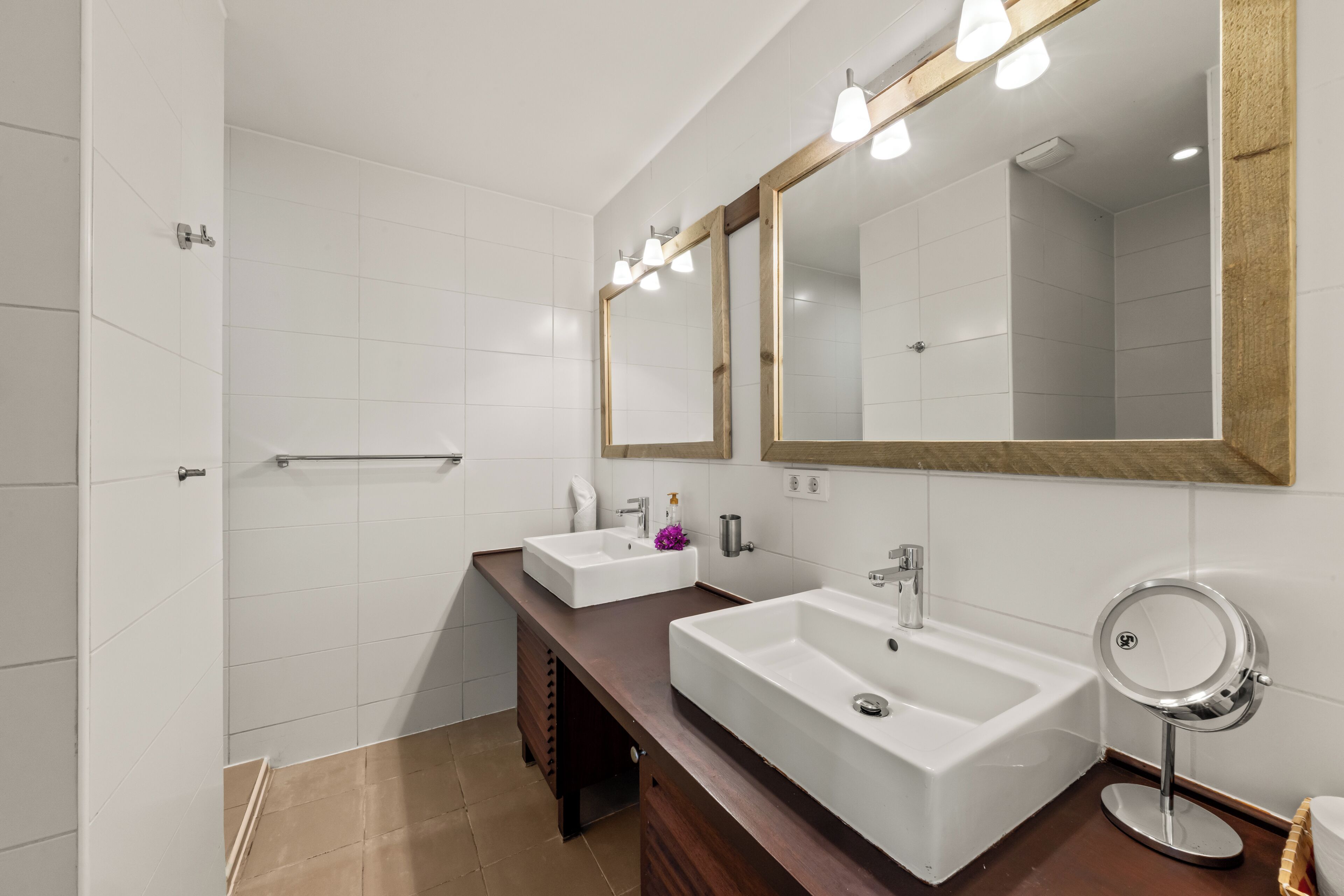 Ein modernes Badezimmer mit zwei Waschbecken, einem Spiegel und einer Dusche.