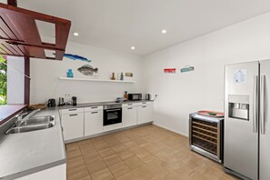 Een moderne keuken met witte kasten, een roestvrijstalen koelkast, een inbouwoven en een waterdispenser.
