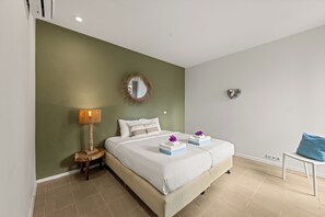 Een hotelkamer met een bed, nachtkastje, lamp, spiegel en een hartvormige decoratie aan de muur.