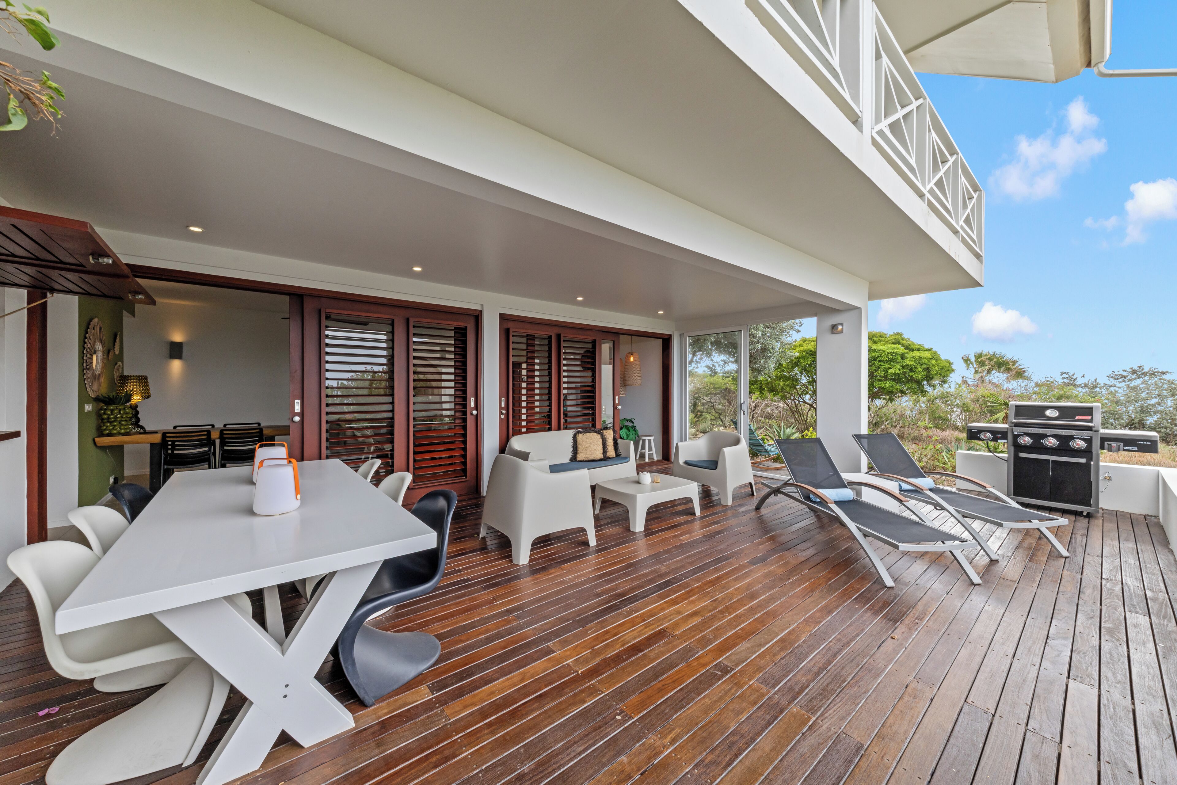 A covered outdoor area with a dining table, chairs, and lounge seating.