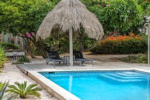 A swimming pool with two lounge chairs and a thatched umbrella. - Ocean View Apartment Bayside, 6 guests - Boca Gentil, Jan Thiel area (Jan Thiel)