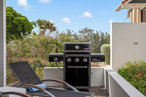 An outdoor patio with a Coleman grill, a lounge chair, and a view of the surrounding greenery. - Ocean View Apartment Bayside, 6 guests - Boca Gentil, Jan Thiel area (Jan Thiel)