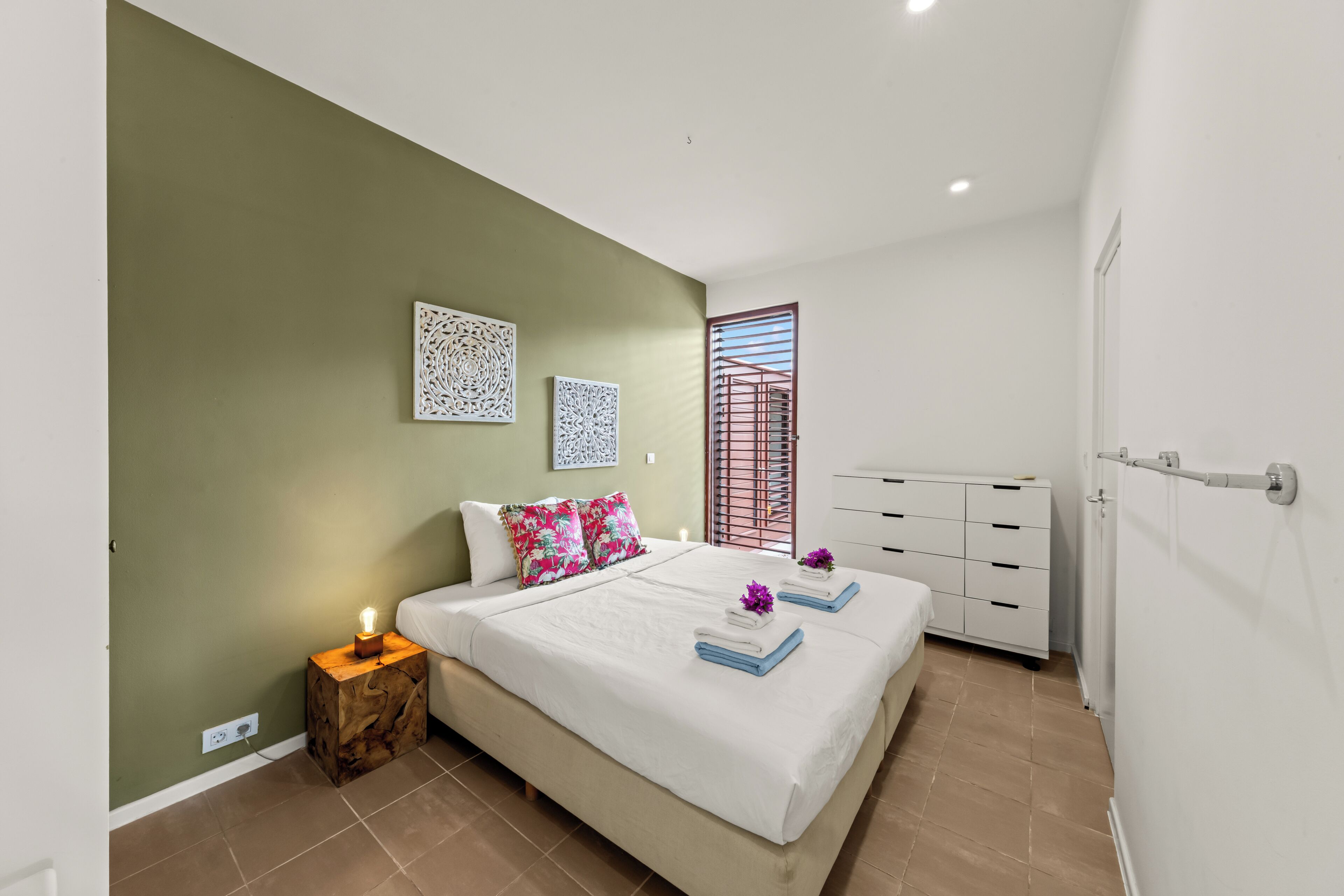Un dormitorio con cama, mesita de noche, cómoda y ventana con vistas.