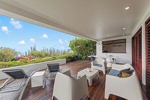 Een overdekt terras met uitzicht op een tuin en de lucht.