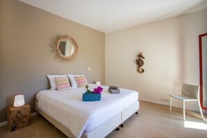 Ein Schlafzimmer mit einem großen Bett, einem Nachttisch mit Lampe, einem Sessel und einer Wanddekoration.