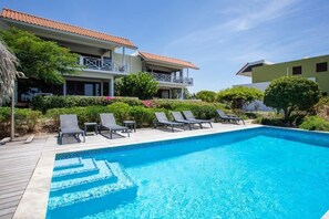 Ein Schwimmbad mit Liegestühlen und einem Gebäude mit Balkon.