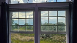 Ein Zimmer mit einem großen Bogenfenster mit Blick auf ein Feld.