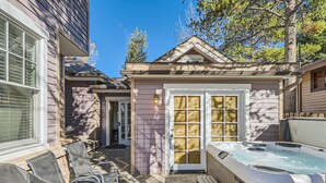 A backyard with a hot tub, covered patio chairs, and a door leading to a covered porch. - Home in Downtown Breck w/ free bus to lifts, walkable to Main St and Peak 9 (Breckenridge)