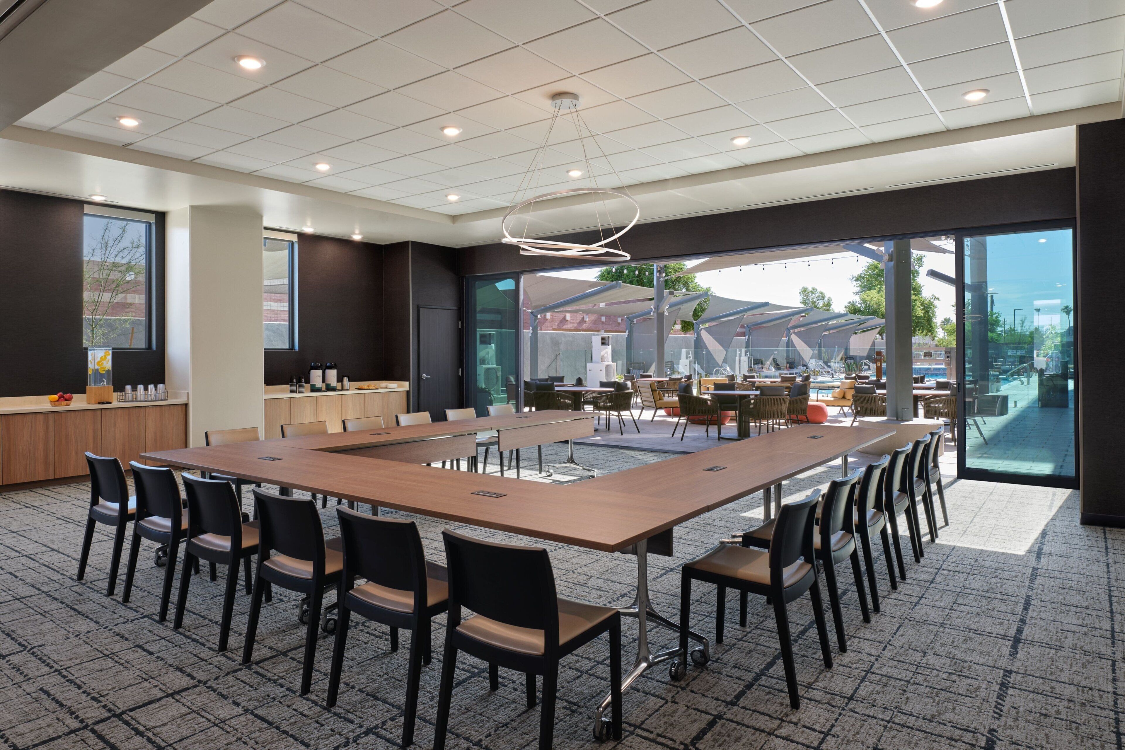 A modern conference room with a large table, chairs, and a view of the outdoors.